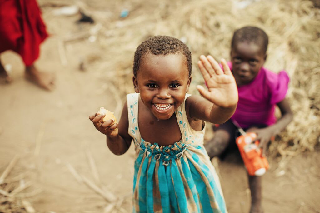 Little girl in a blue dress waving to the camera